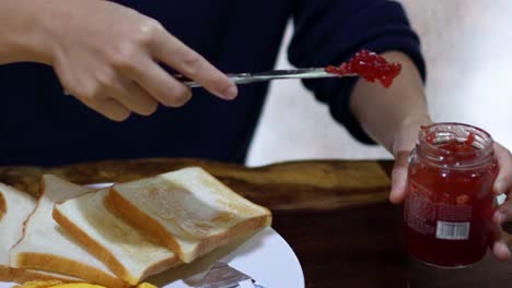 spreading jam on toast slices for breakfast