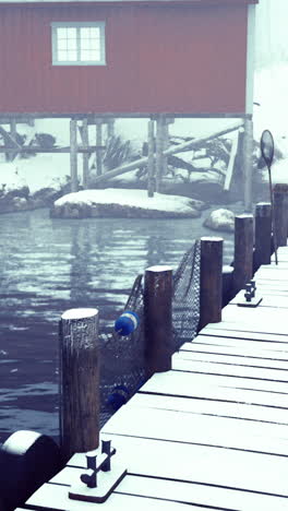 snow covered dock with a red cabin near calm water during winter