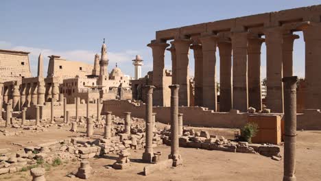 panning shot of the ruins of ancient temple of luxor with a mosque and minaret