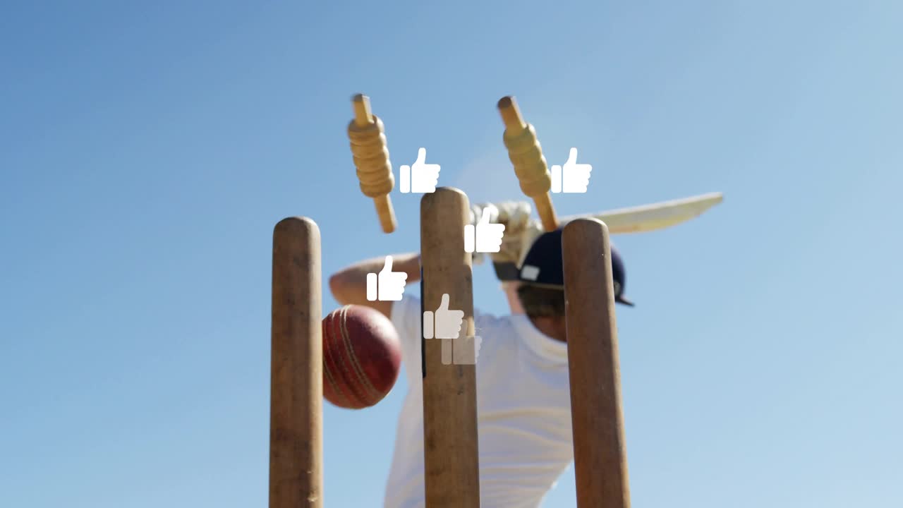 Høyrehendt slagmann svinger mot innkommende cricketball, som får flygende bails blant tommel opp-ikoner