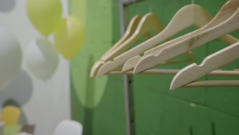 wooden clothes hangers against a green wall with balloons