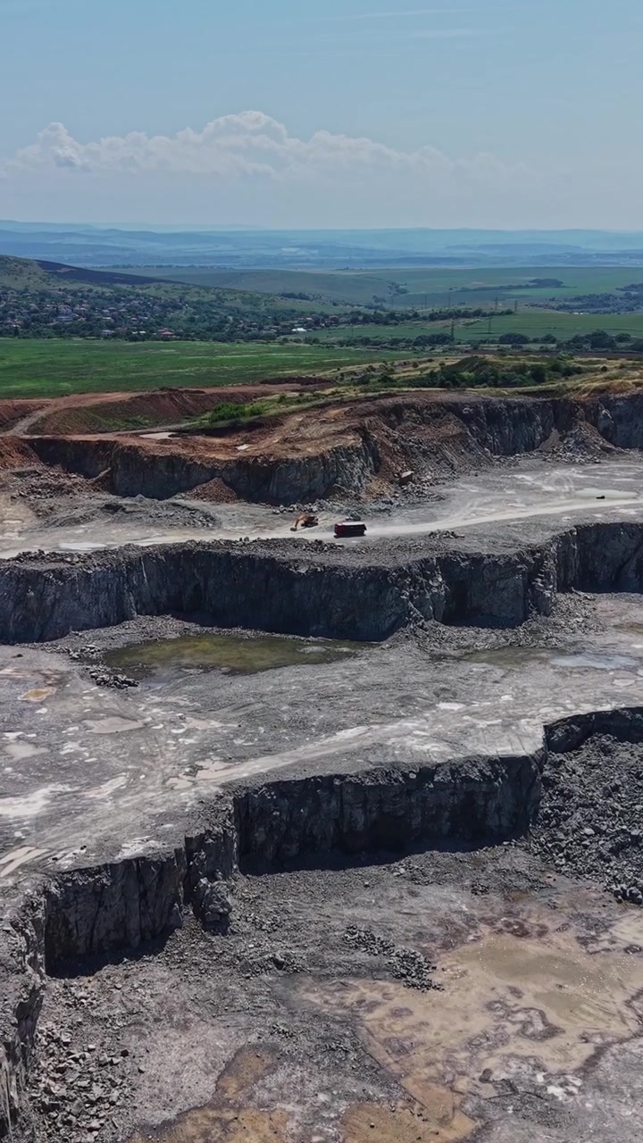 Large quarry site with machinery and open landscape under blue sky