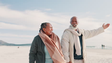 Senior,-couple-and-pointing-on-beach-with-smile