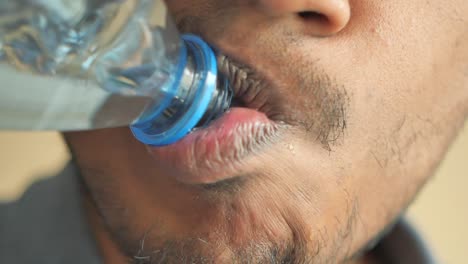 person drinking water from a plastic bottle