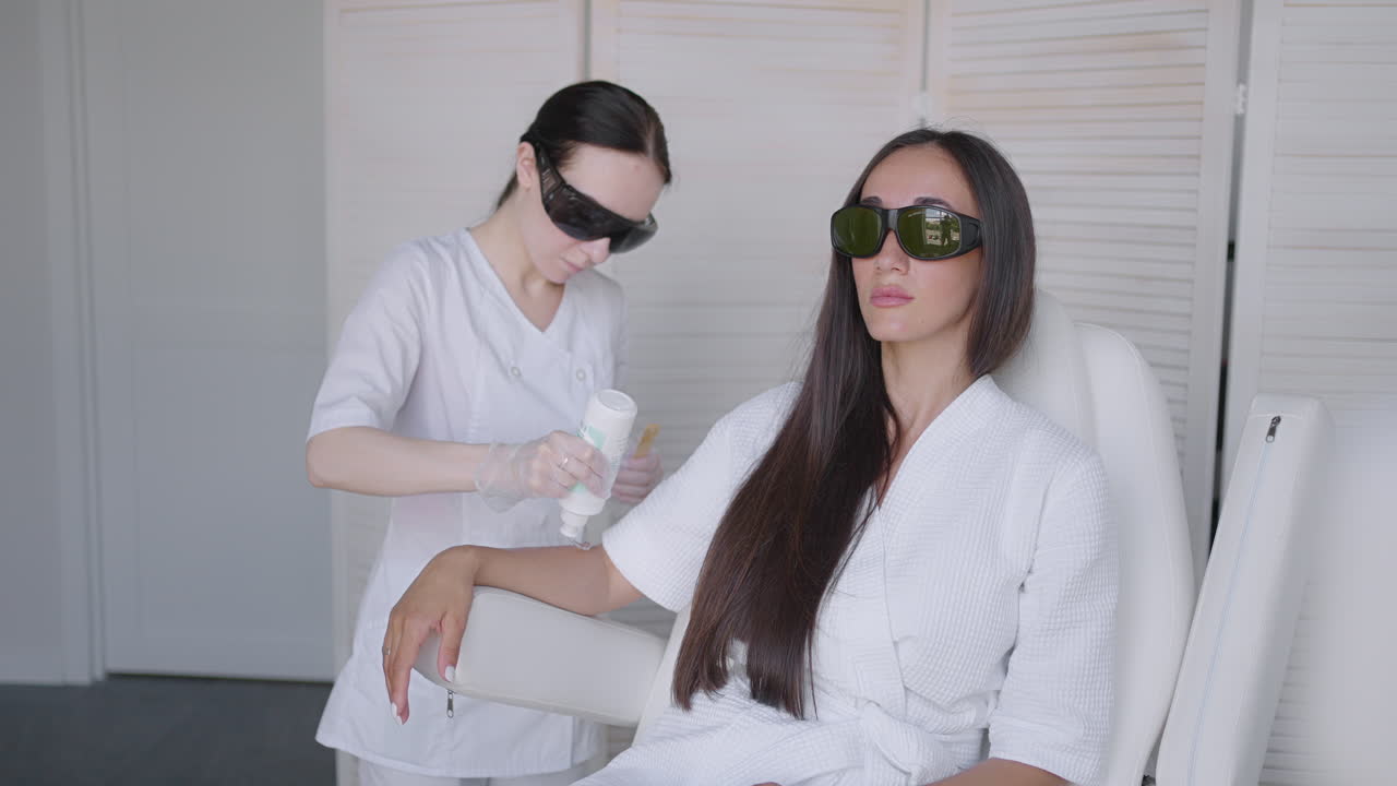 손에 머리카락을 제거하는 절차. 다이오드 레이저 트래킹 움직이는 카메라에서 레이저 머리카락 제거. 여성 미용학자가 여성 손에 레이저 머리카락 제거 젤을 적용합니다. photoepilation 신체 관리 개념.
