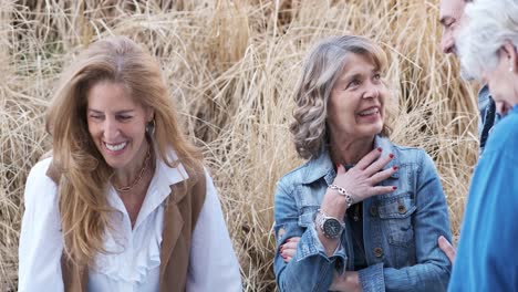 cheerful women talking to crop friends against dry grass