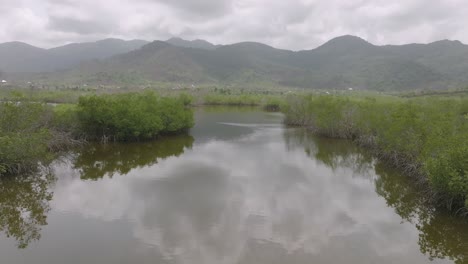 Aerial-flyover-of-a-river-that-is-going-to-the-ocean-with-mountains-in-the-background-in-Sierra-Leone,-Africa