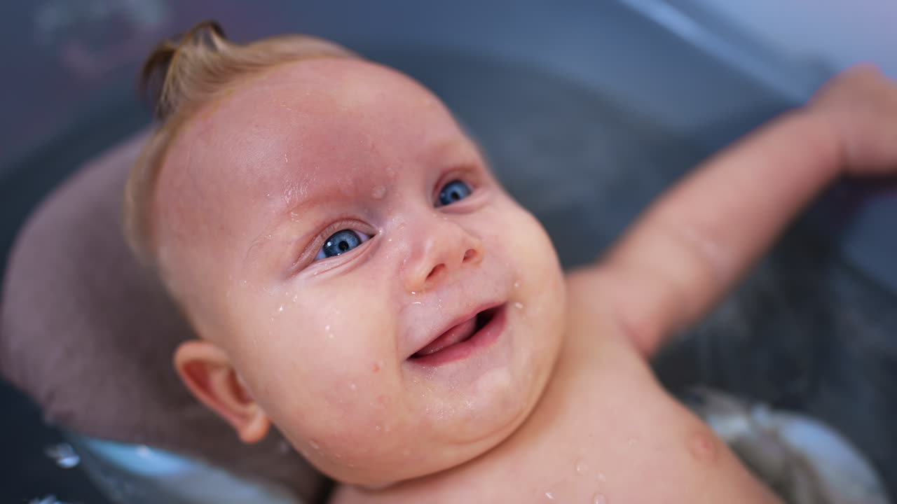 Lovely relaxed Caucasian infant baby lies in the bath tub. Cute child smiling adorably. Close up.