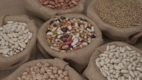 Legumes-dry-mixed-various-beans,-lentils,-chickpeas-rotating-on-jute-bowl