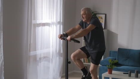 Fitness-Y-Estilo-De-Vida-Saludable-En-Un-Hombre-Adulto-De-Mediana-Edad-Está-Entrenando-Con-Una-Bicicleta-De-Ejercicio-En-La-Actividad-Deportiva-De-La-Sala-De-Estar-En-Autoaislamiento