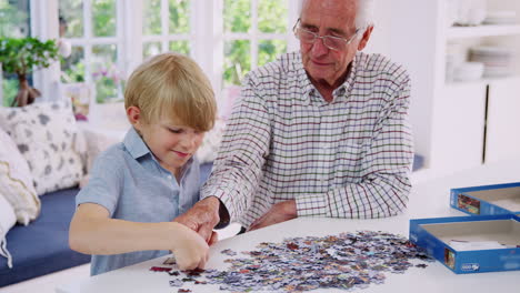 senior man and grandson doing jigsaw puzzle together at home