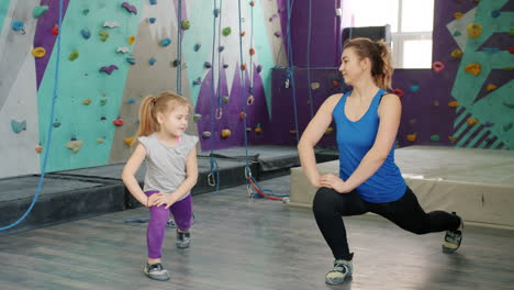 mother and daughter stretching in a rock climbing gym
