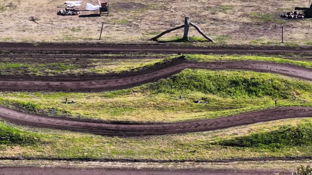 Foto a plongée di bambini su moto da cross che corrono in un circuito da motocross erboso