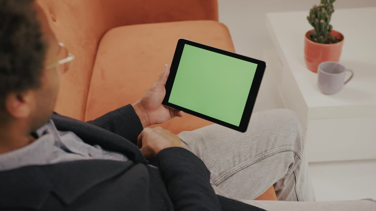 아이패드를 수평으로 사용하고 응용 프로그램에서 사진을 스와이프하는 안경을 쓴 젊은 남자