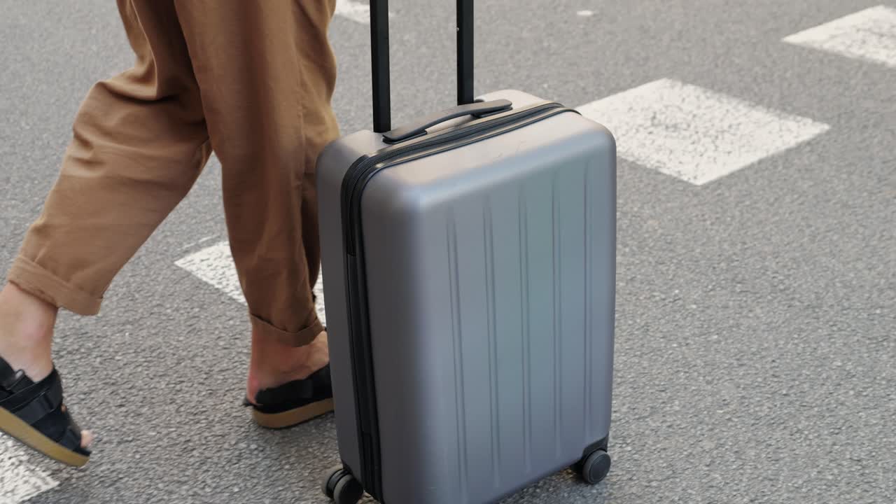 Persoon die met een koffer over een zebrapad loopt