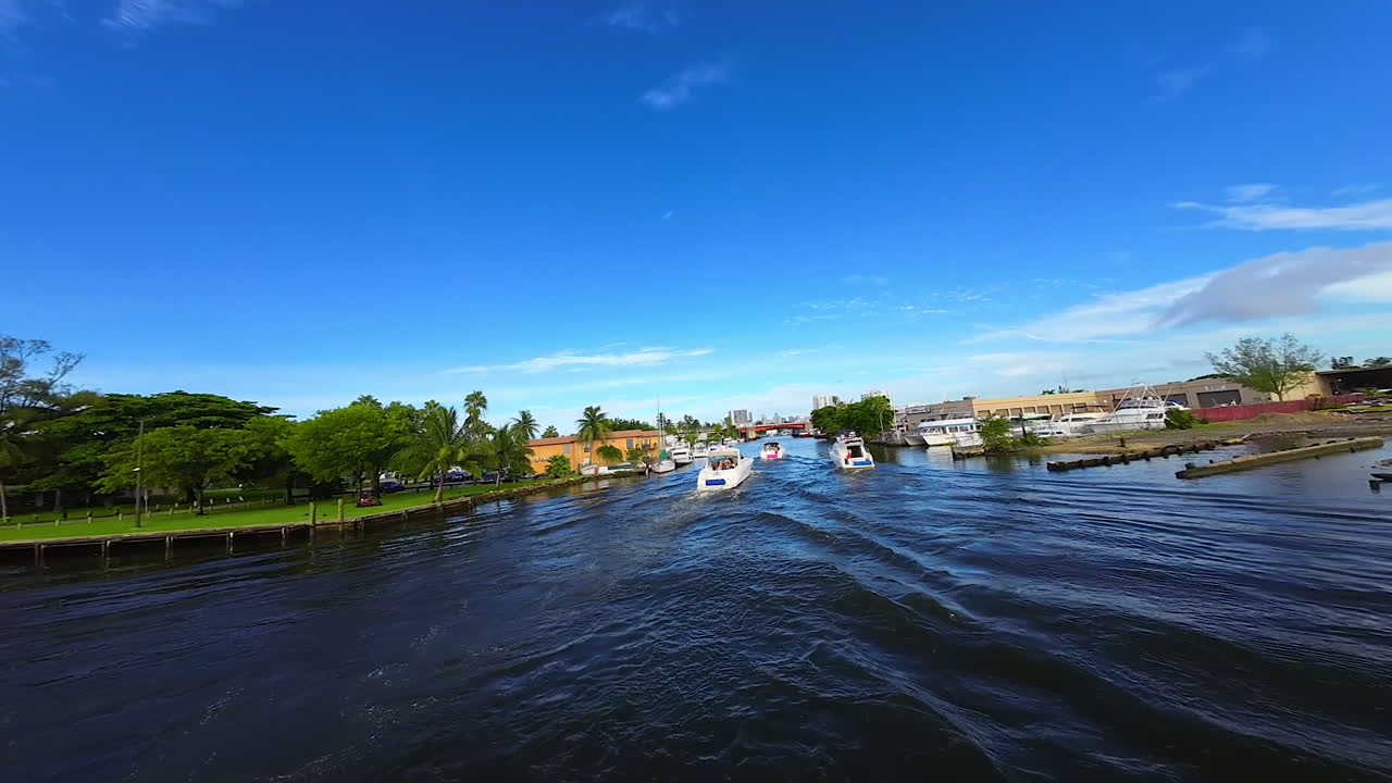 Circling around the modern yacht floating by the channel. Catching up with three boats sailing in front. FPV drone footage.