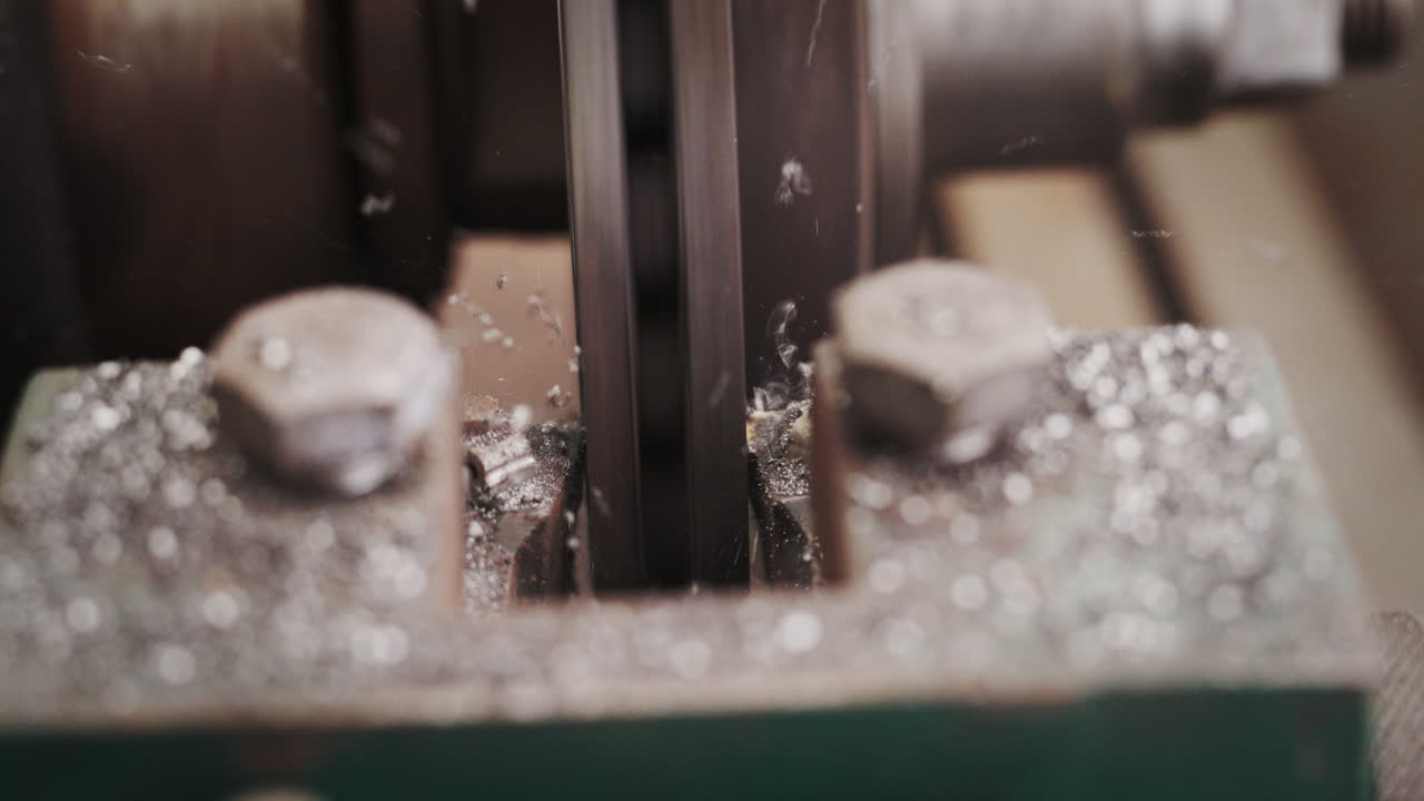Close-up of a metal lathe cutting steel, showing flying shavings and industrial manufacturing process