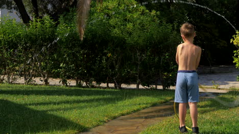 kid playing with hose when watering grass