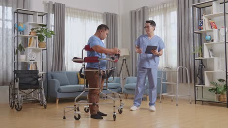 full body side view of asian male nurse with a tablet explaining how to use a walker to a patient during a physical therapy at home