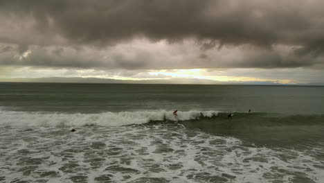 surfers move against the horizon's soft glow.