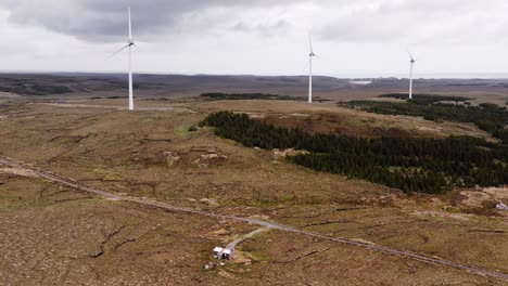 wide, descending drone shot of a moorland wind farm and a shieling