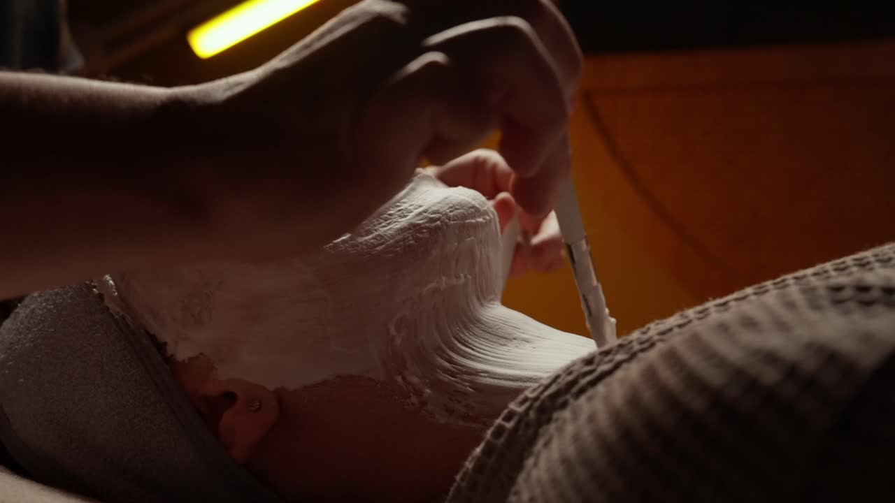 Estetista che applica una maschera viso sul viso e sul collo di una donna in una spa