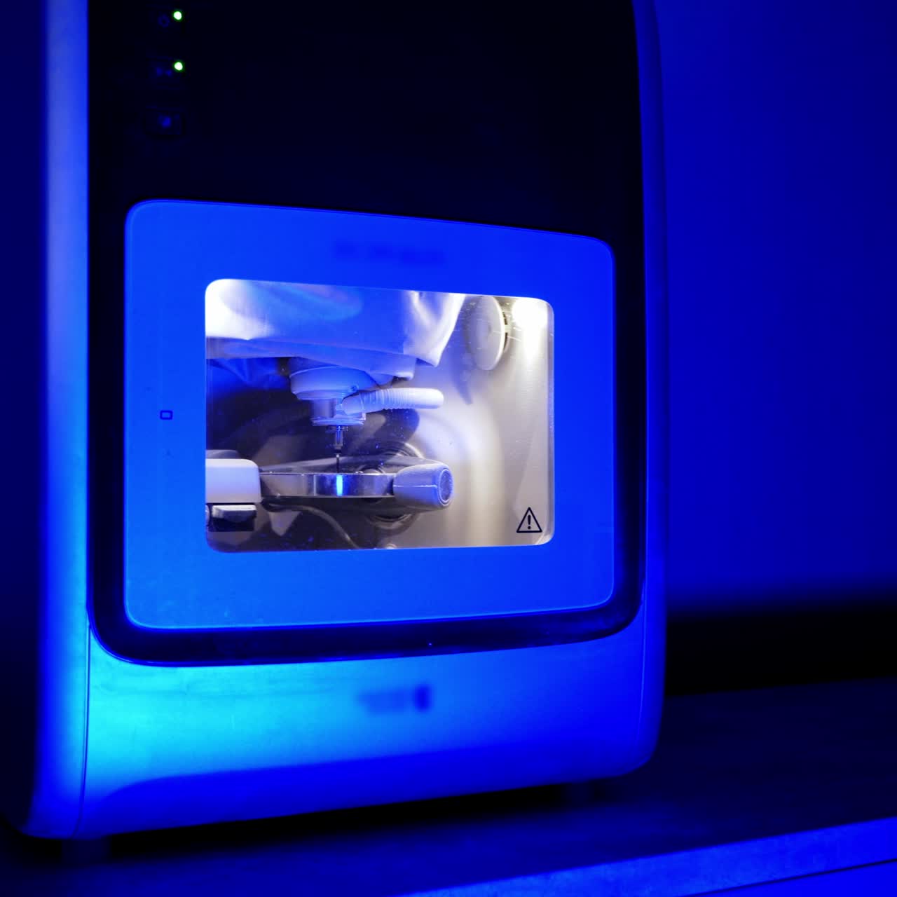 Dental milling machine in blue light. Modern medical device in dental laboratory. Work of advanced equipment in stomatology