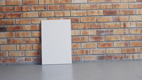 video of white canvas sign with copy space on floor against brick wall background