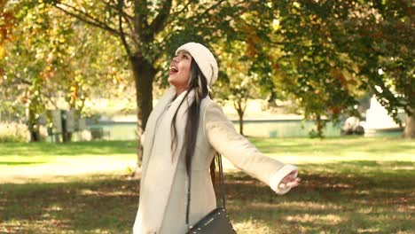 hermosa chica mira a su alrededor las frías hojas de otoño en un parque de la ciudad