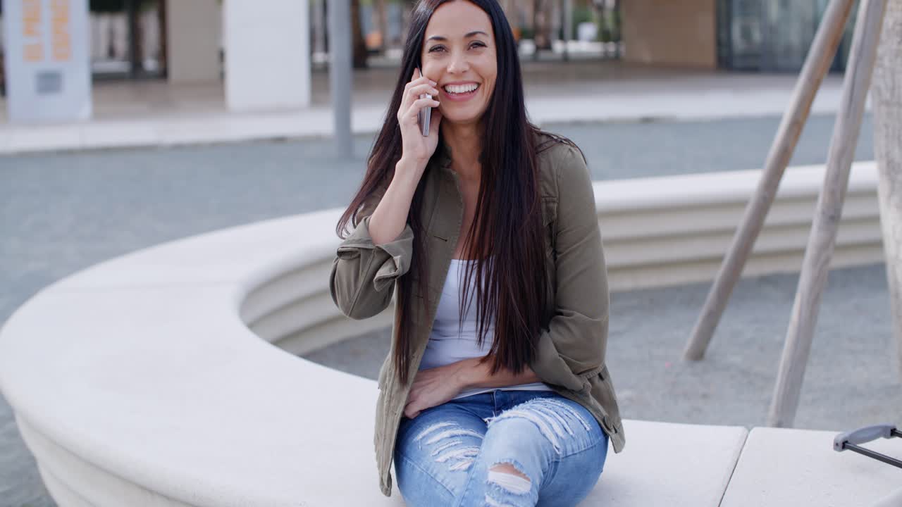 una mujer joven riendo mientras conversa en un móvil.