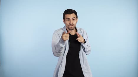 cropped portrait of glad caucasian guy in blue shirt fooling around in studio. indoor footage of happy dark haired man dancing on blue background