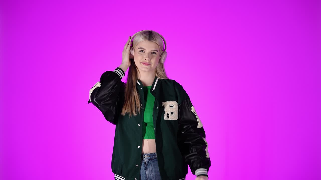 Bella giovane donna che si gode l'ascolto della musica con le cuffie, sfondo viola.