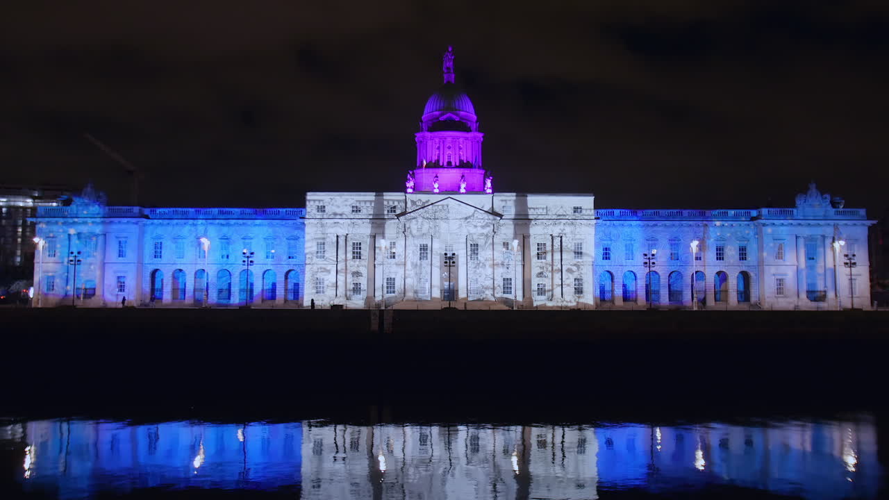 겨울의 불빛으로 조명된 관습 집의 정적, 밤에 리피 강에 반사됩니다.