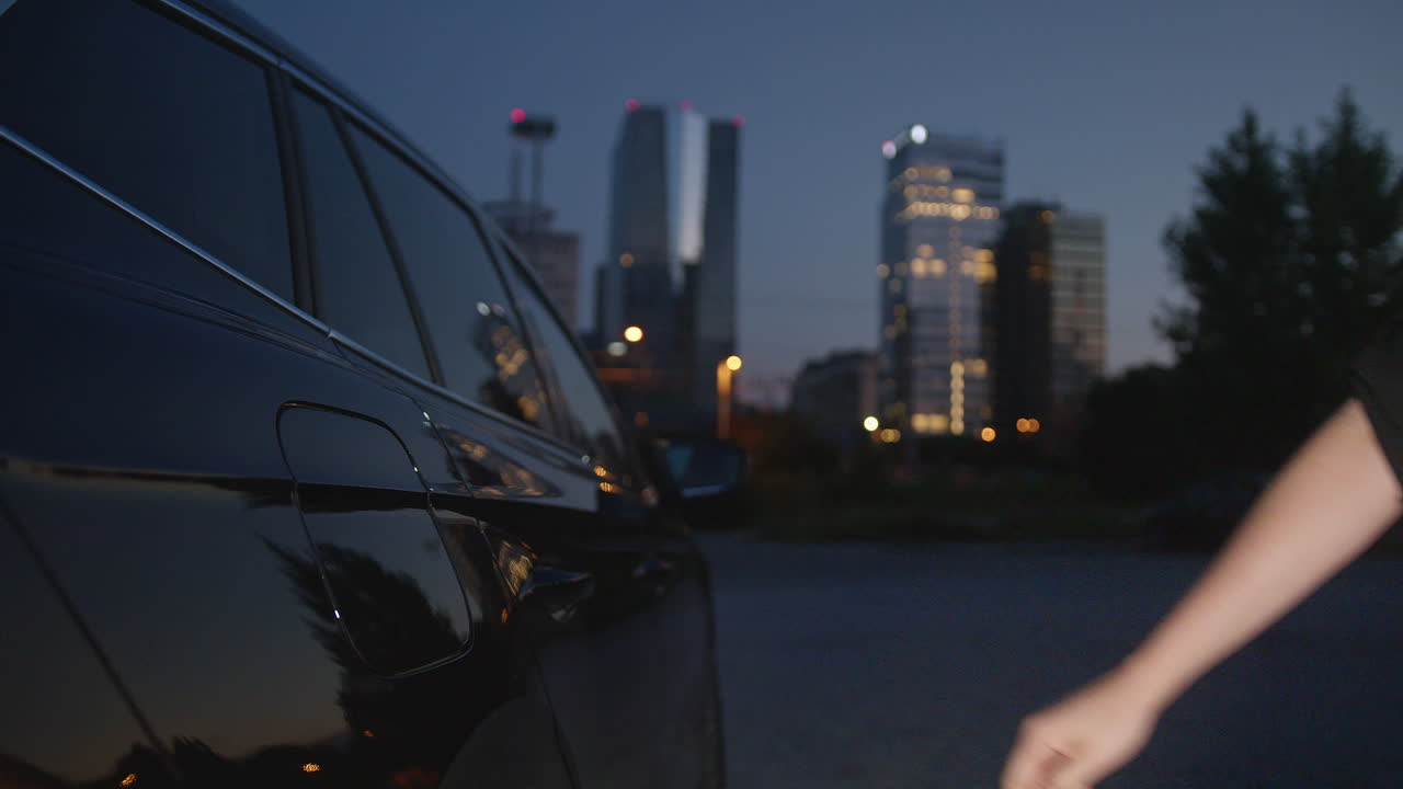 Mani femminili che collegano il caricabatterie in un'auto elettrica, primo piano.