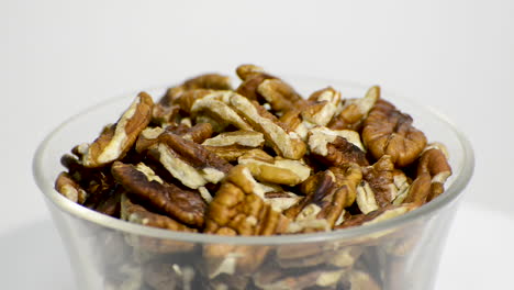 Transparent-glass-bowl-with-pecan-nuts-rotating-on-a-white-background