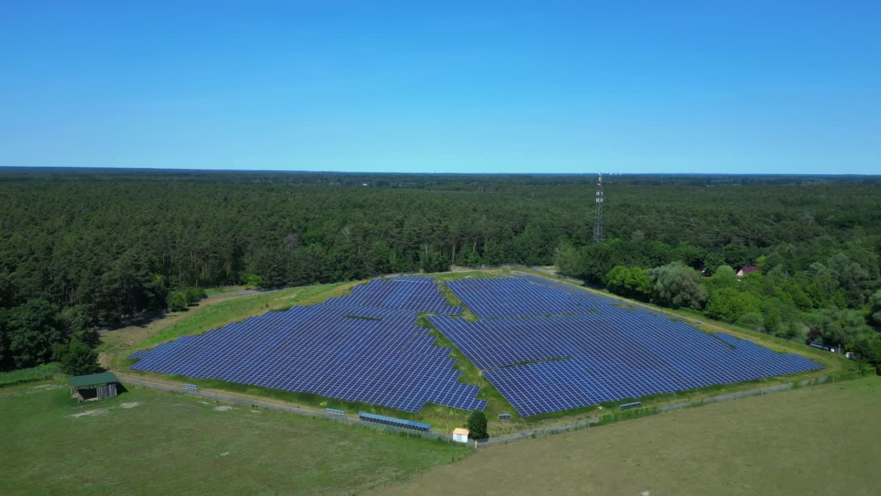 Photovoltaic panels providing clean energy in a solar farm on hill near a forest in Germany. Lovely aerial view flight panorama orbit drone