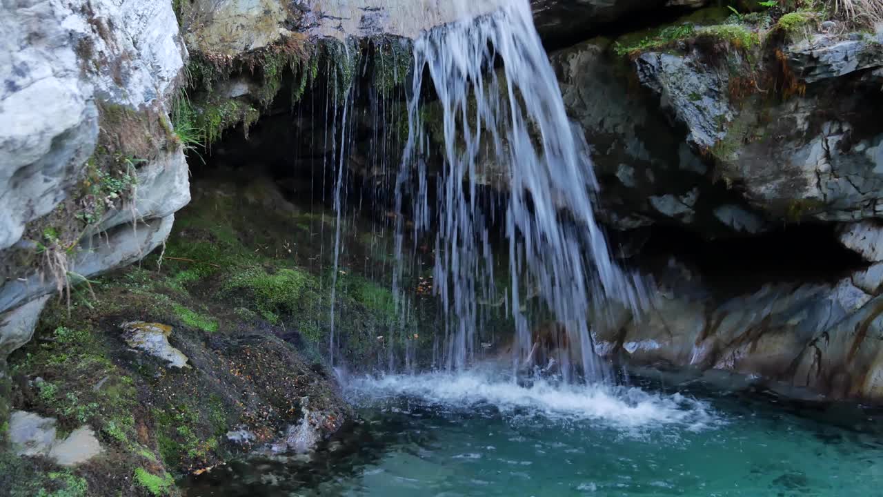 poco atractiva caverna oscura vista detrás de la fría cascada de la selva tropical cubierta de musgo