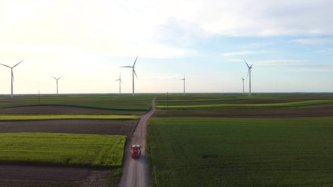 드론은 4k의 풍차에서 녹색 필드에서 트랙터가 지나가는 것을  ⁇ 습니다.