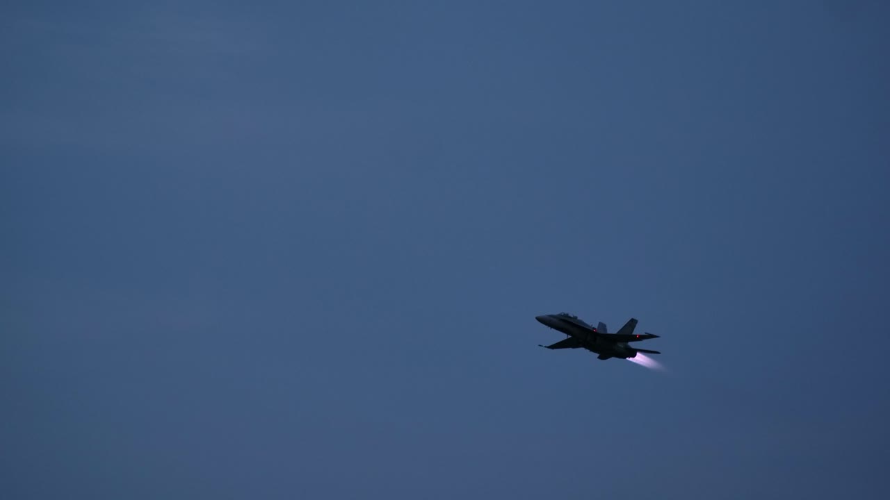 Silhouette of a F-18 Jet Fighter Lighting the Afterburner DUSK