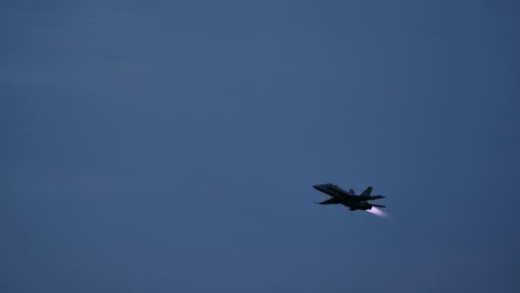 silhouette of a f-18 jet fighter lighting the afterburner dusk