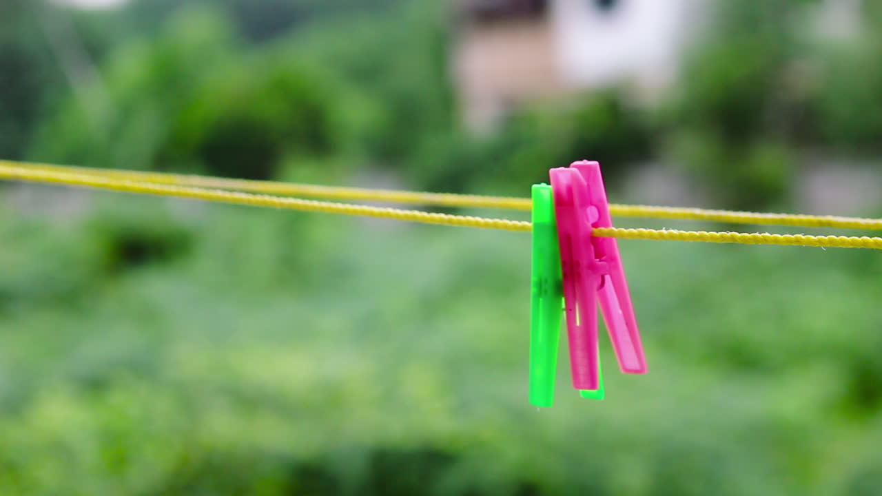 Closeup shot of colorful cloth clips on rope outdoors. Laundry pegs hanging in fresh air, everyday life and household concept. Perfect for lifestyle, cleaning and home stock footage