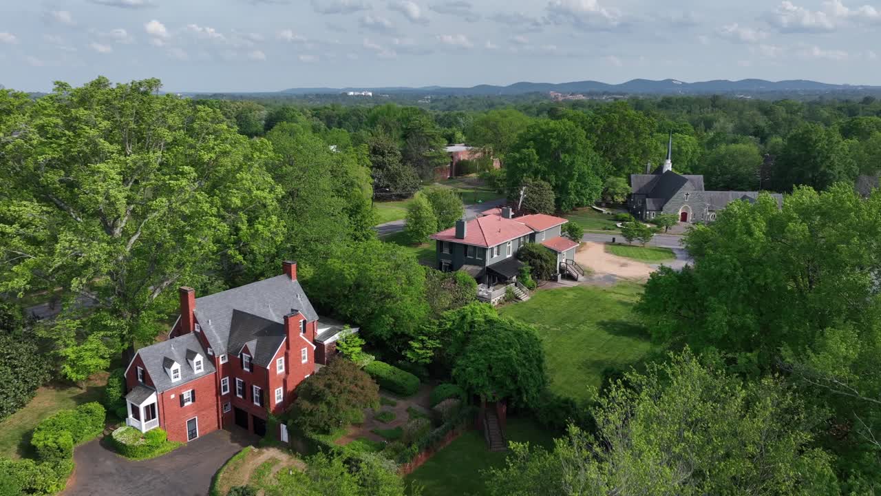 Historic mansion between green trees in small american suburb neighborhood. Church tower and car on street in quiet area of Lynchburg, Virginia.