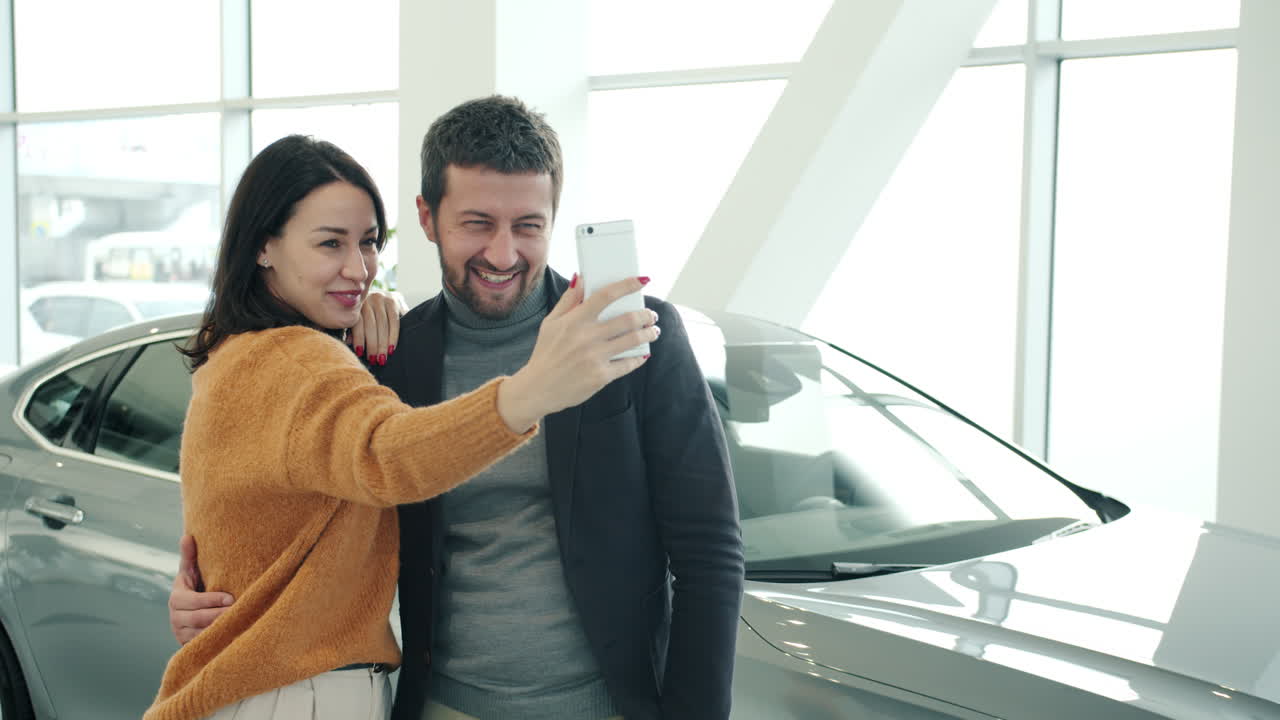 Couple taking selfies at car dealership
