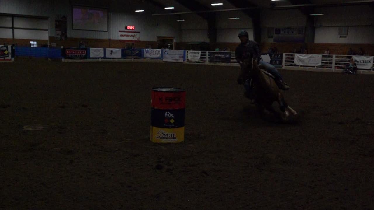 Cavallo e cavaliere che competono in una corsa a barili indoor