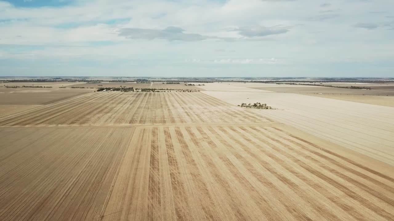 Sideways aerial footage over dry paddocks after harvest near Wedderburn, Victoria, Australia, May 2021.