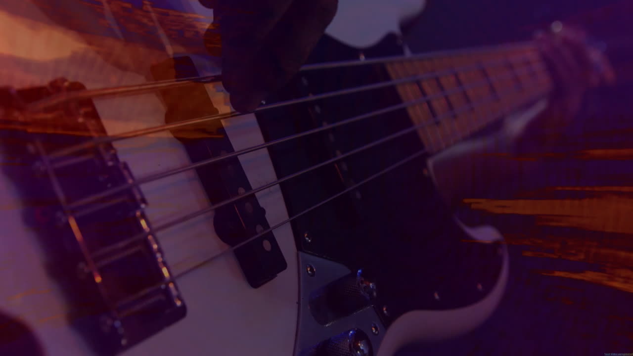 Studio musician hand plucking electric bass guitar under purple lighting, with orange light streaks