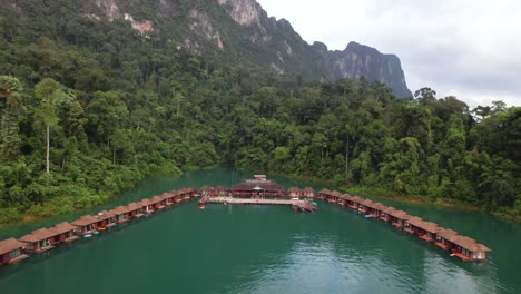 4k drone video flying away from the floating bunglows that you can stay at in khao sok national park, thailand