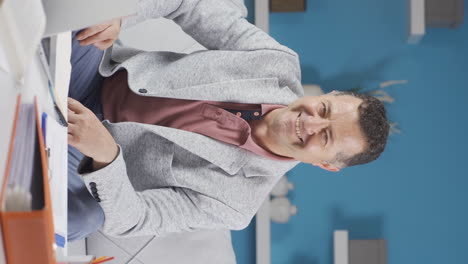 Vertical-video-of-Home-office-worker-old-man-smiles-at-camera.