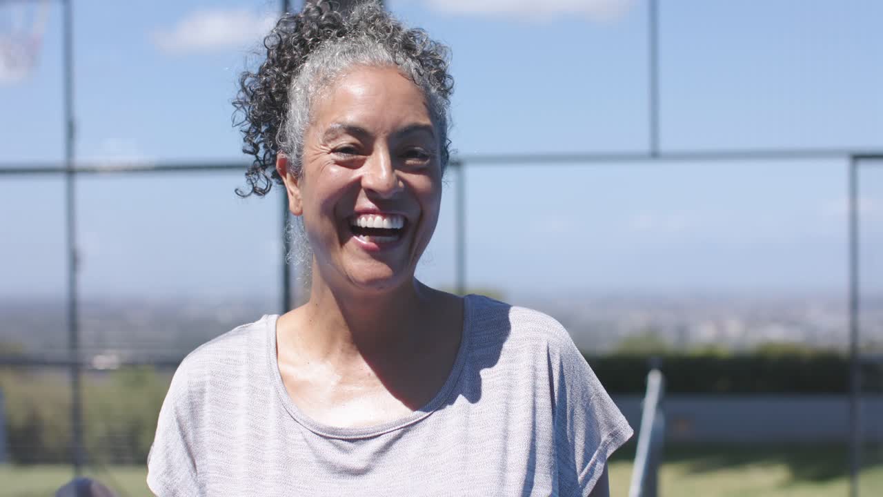 Senior African American woman reacting to paddle entering, smiling and laughing on fenced court