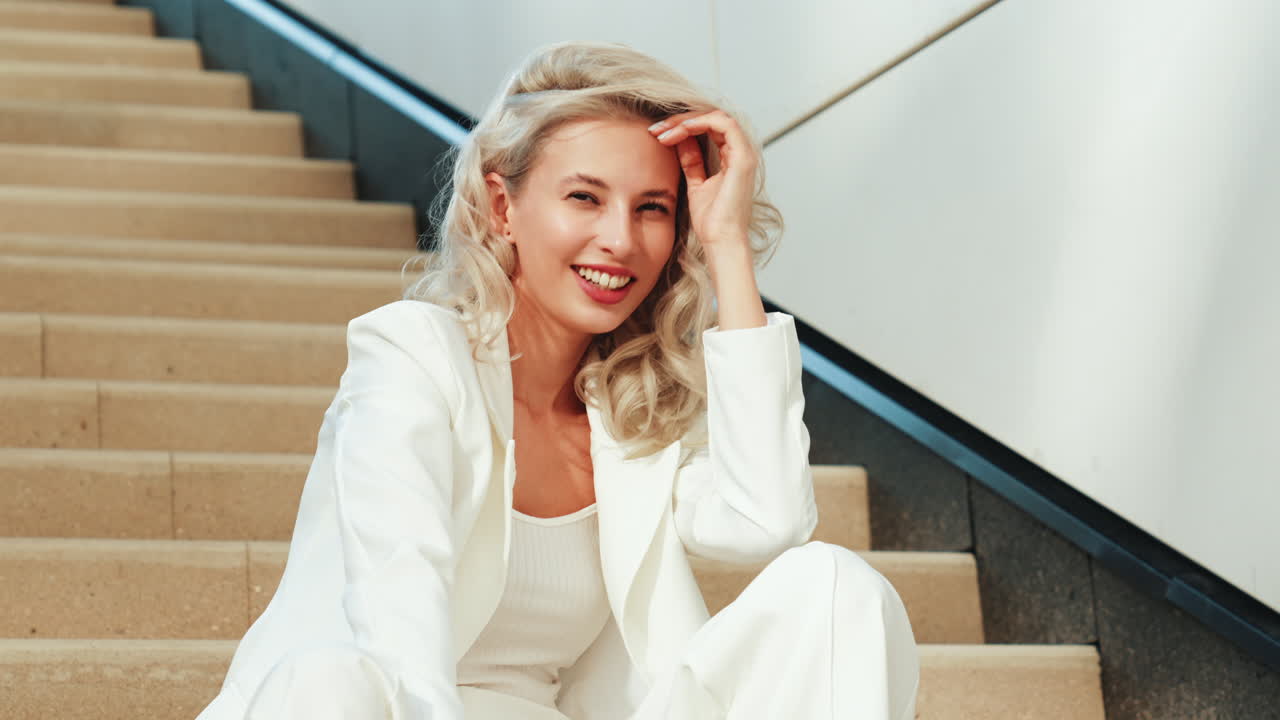 женщина в белом костюме сидит на лестнице